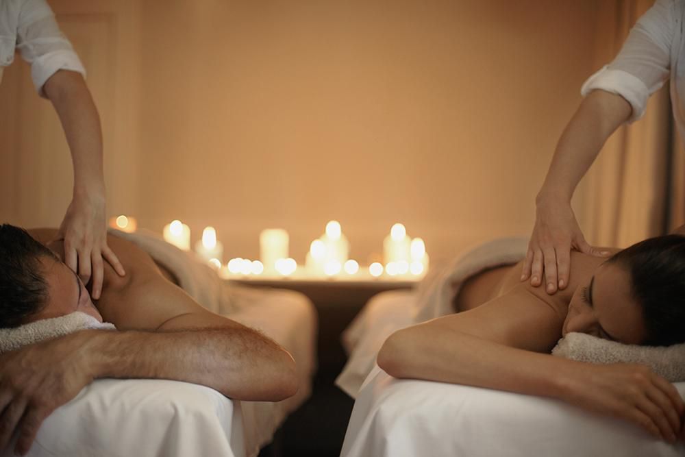 Pareja recibiendo un masaje simultáneo a la luz de las velas